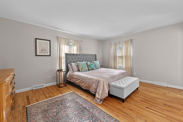 bedroom featuring baseboards, multiple windows, wood finished floors, and visible vents