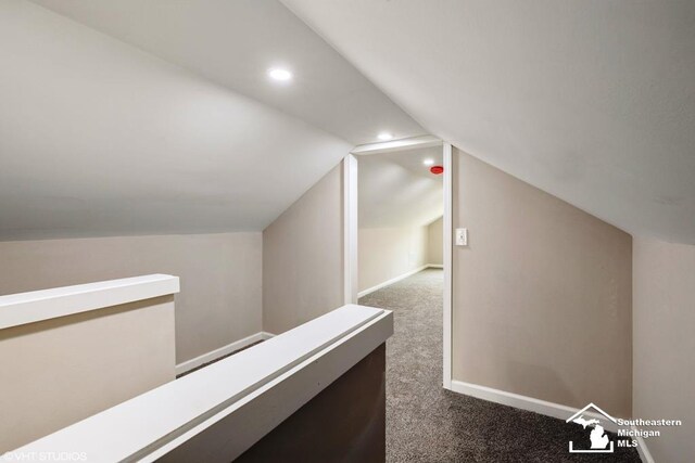 hall with recessed lighting, baseboards, dark colored carpet, and lofted ceiling