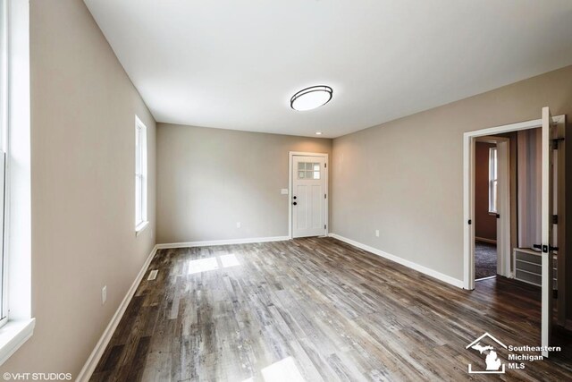unfurnished living room featuring baseboards, wood finished floors, and visible vents