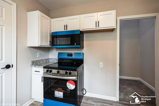 kitchen featuring black microwave, white cabinetry, and stainless steel range with electric cooktop