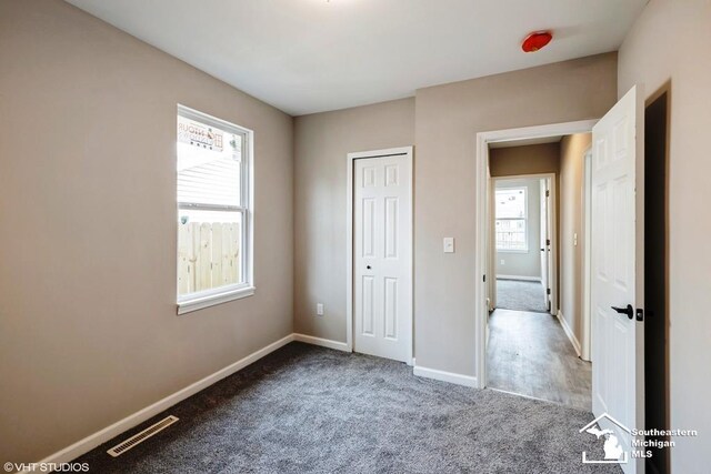 unfurnished bedroom with visible vents, baseboards, carpet floors, and multiple windows