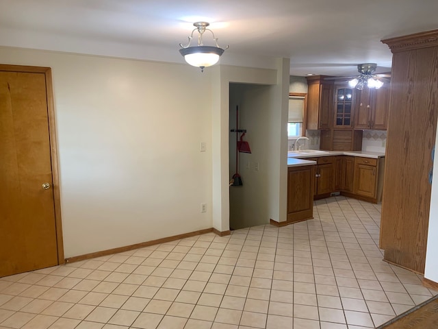 kitchen featuring a ceiling fan, light countertops, brown cabinets, tasteful backsplash, and a sink
