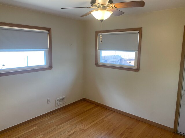 spare room with ceiling fan, visible vents, baseboards, and light wood finished floors