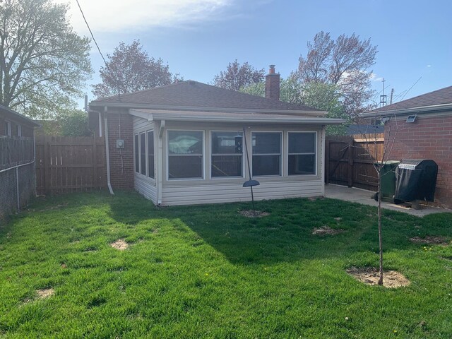 rear view of house with a fenced backyard, a chimney, a lawn, and a shingled roof