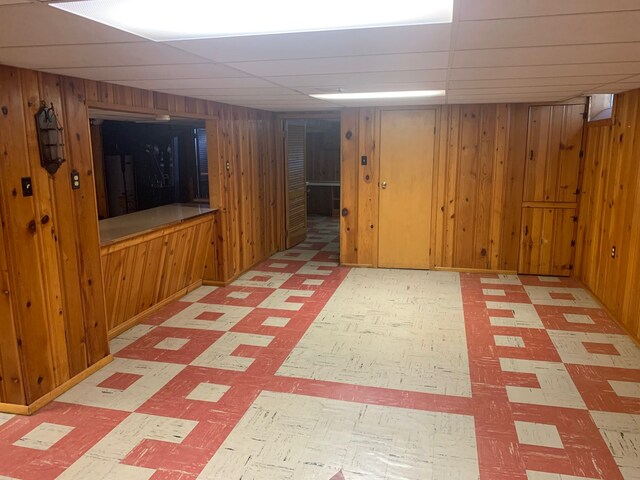 finished below grade area featuring tile patterned floors and wood walls