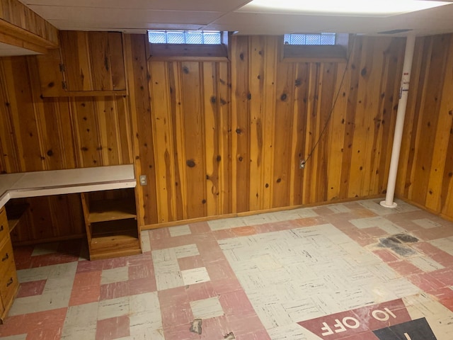 basement featuring tile patterned floors and wood walls