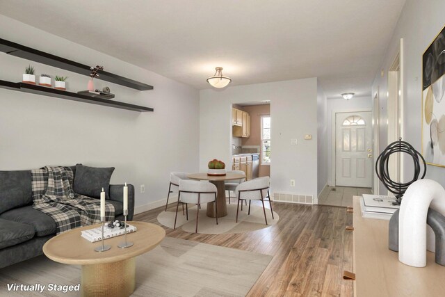 living area featuring baseboards, visible vents, and wood finished floors