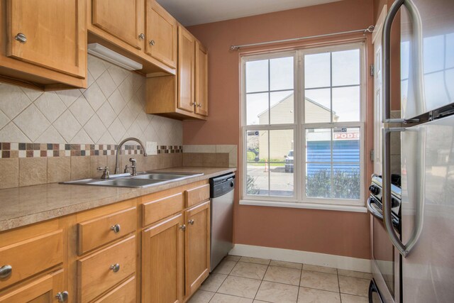 kitchen featuring baseboards, light countertops, a sink, appliances with stainless steel finishes, and light tile patterned floors