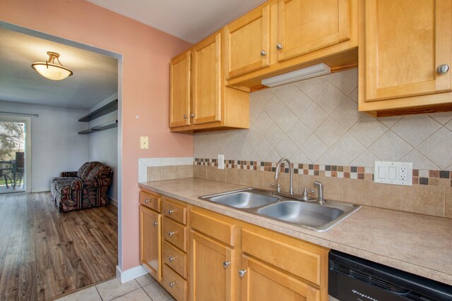kitchen featuring backsplash, light countertops, baseboards, a sink, and dishwashing machine