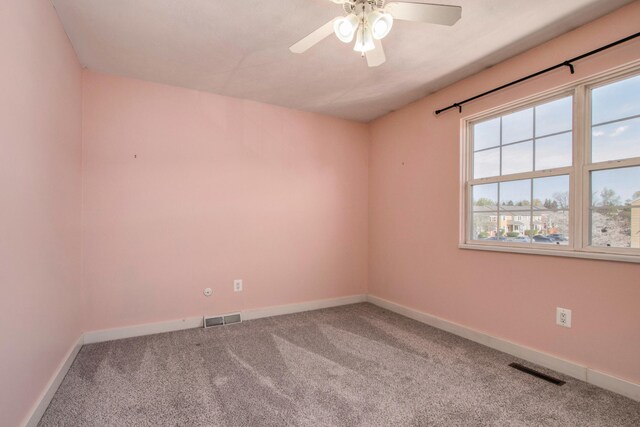 carpeted empty room with visible vents, a ceiling fan, and baseboards
