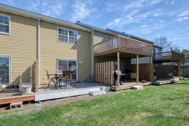 rear view of property featuring fence, a yard, and a deck
