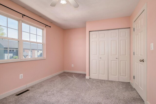 unfurnished bedroom with visible vents, a ceiling fan, a closet, baseboards, and carpet flooring