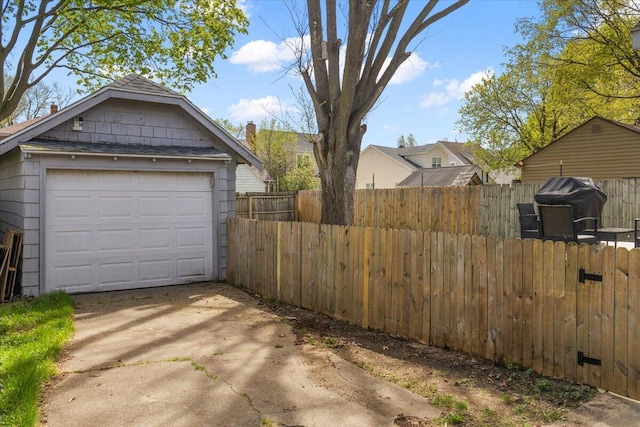 detached garage with fence and concrete driveway