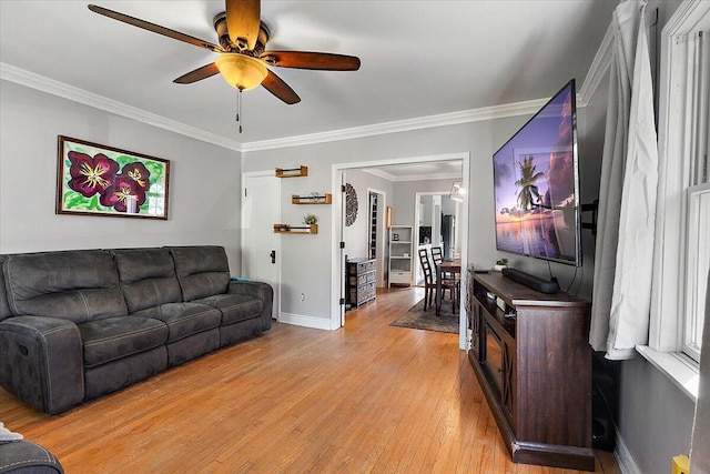 living room with crown molding, baseboards, ceiling fan, and light wood-type flooring