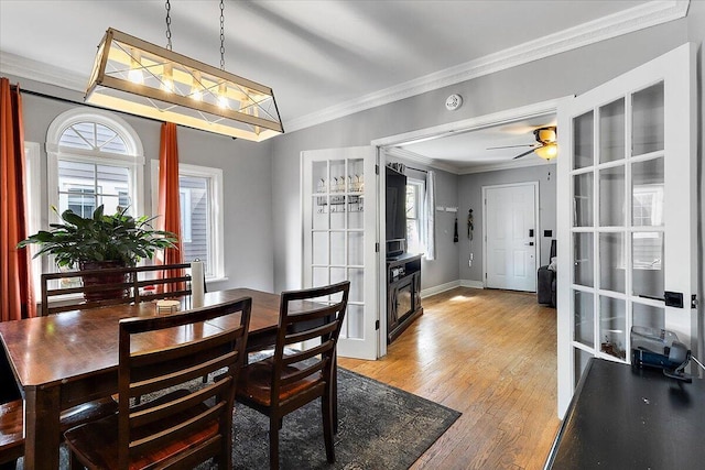 dining area with ornamental molding, baseboards, french doors, a ceiling fan, and light wood finished floors