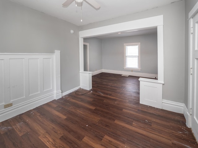 empty room with baseboards, ceiling fan, and dark wood-style floors