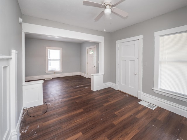 empty room with dark wood-type flooring, baseboards, ceiling fan, and visible vents