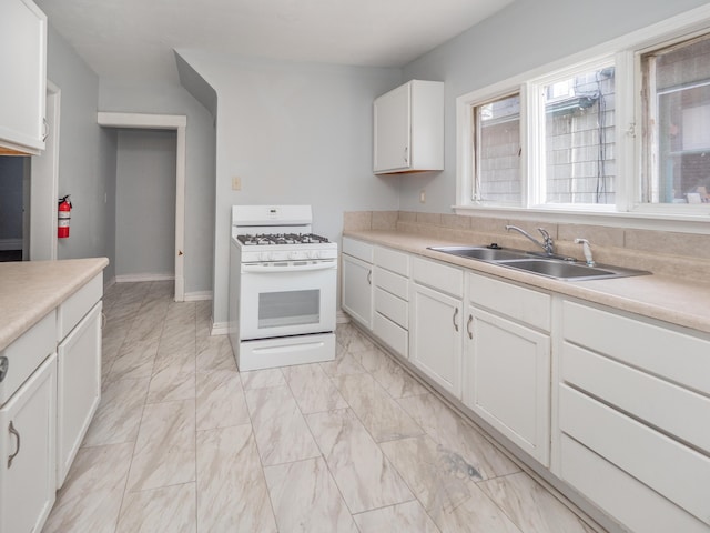 kitchen with white gas range, light countertops, a sink, marble finish floor, and white cabinetry