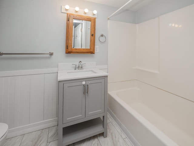 bathroom with vanity, marble finish floor, wainscoting, toilet, and shower / tub combination