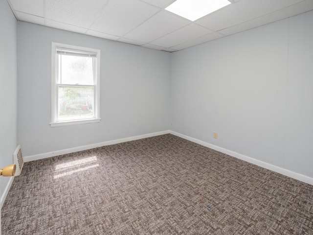 spare room featuring baseboards, visible vents, a drop ceiling, and carpet