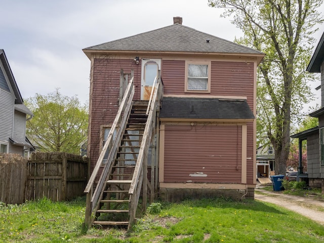 exterior space with fence, a shingled roof, stairs, and a chimney