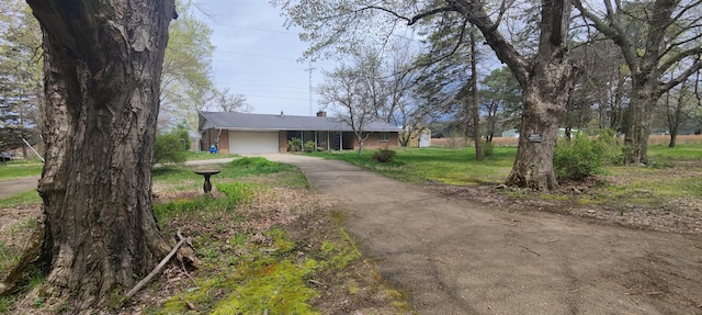 ranch-style home featuring driveway, a chimney, a front lawn, and a garage