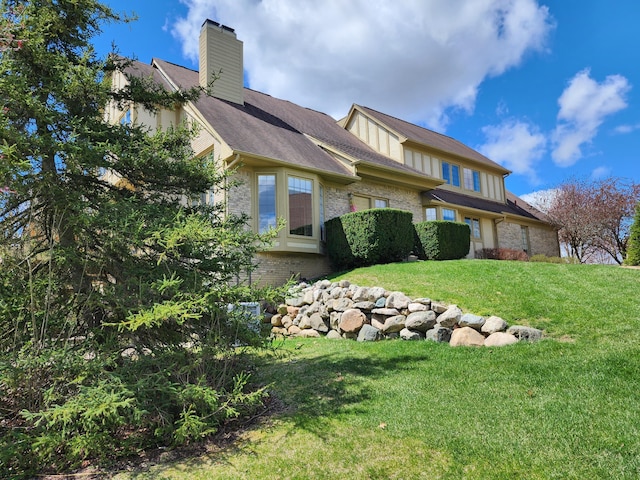 exterior space with a lawn, brick siding, and a chimney