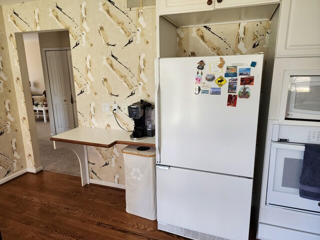 kitchen with white appliances, white cabinetry, dark wood finished floors, and visible vents