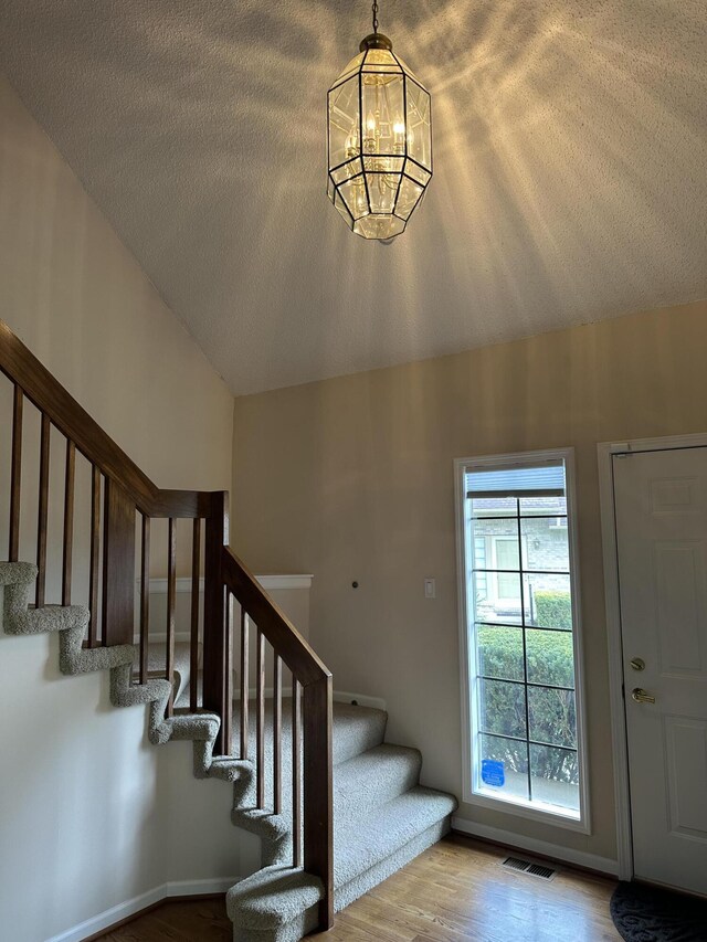 interior space with stairway, a notable chandelier, wood finished floors, and visible vents