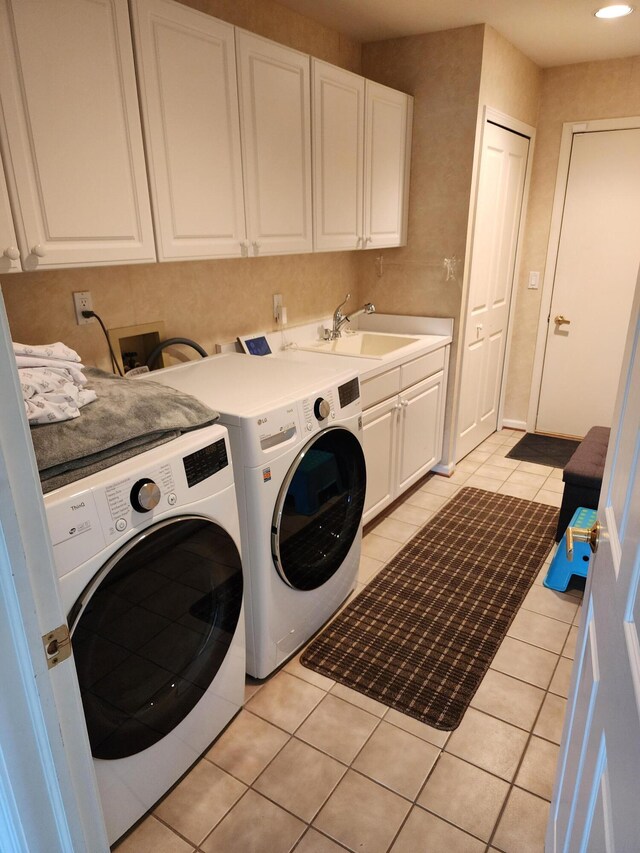 laundry area with a sink, cabinet space, light tile patterned flooring, and washing machine and clothes dryer