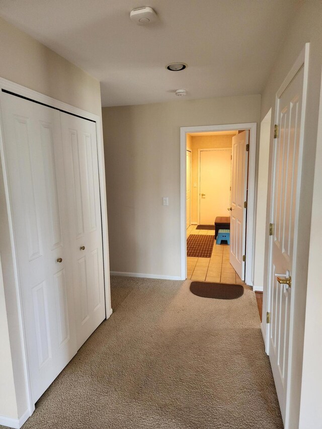 hall with baseboards and light carpet