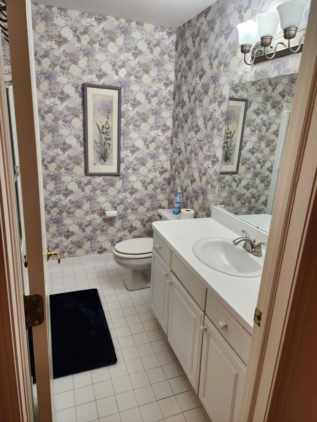 bathroom with tile patterned flooring, vanity, toilet, wallpapered walls, and a chandelier