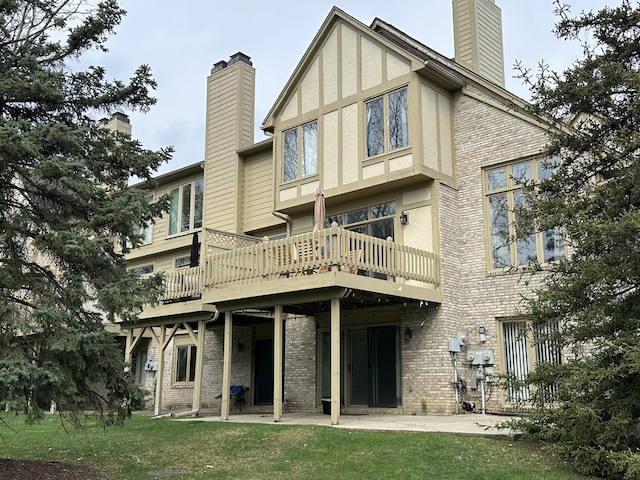 back of house featuring a lawn, brick siding, a chimney, and a patio area