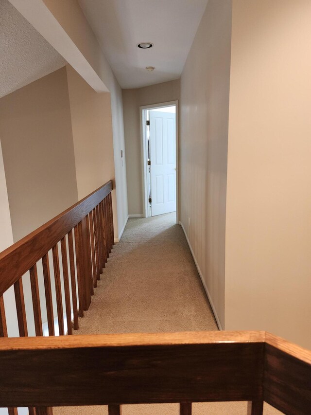 corridor featuring light colored carpet and baseboards