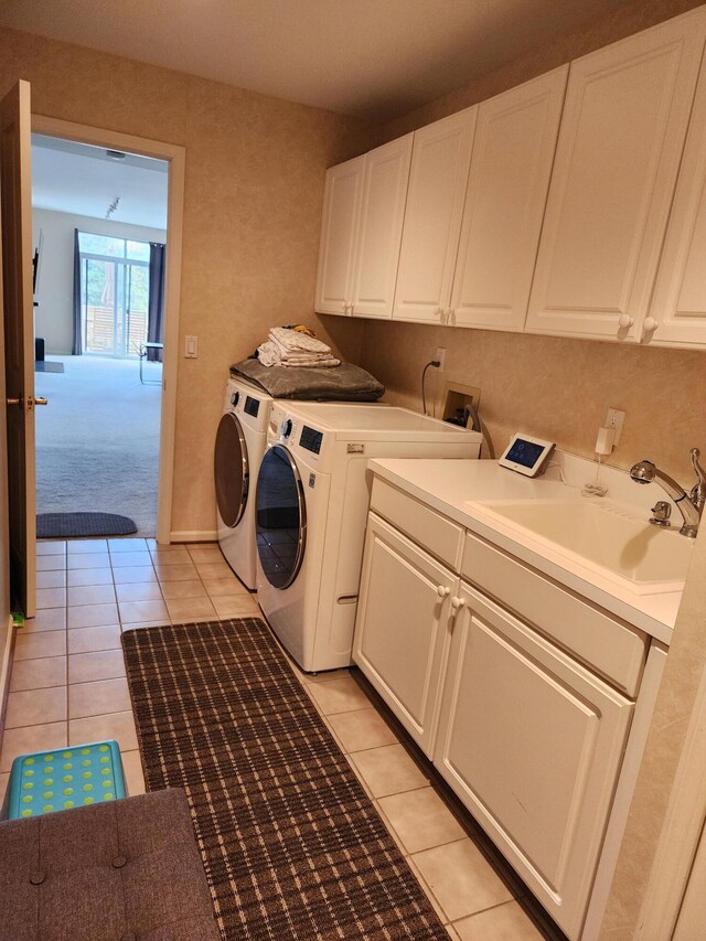 washroom featuring a sink, cabinet space, light tile patterned flooring, and washer and clothes dryer