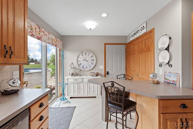 3136 Planeview Dr, Adrian, MI 49221 - kitchen featuring light countertops, a kitchen bar, light tile patterned floors, and dishwasher