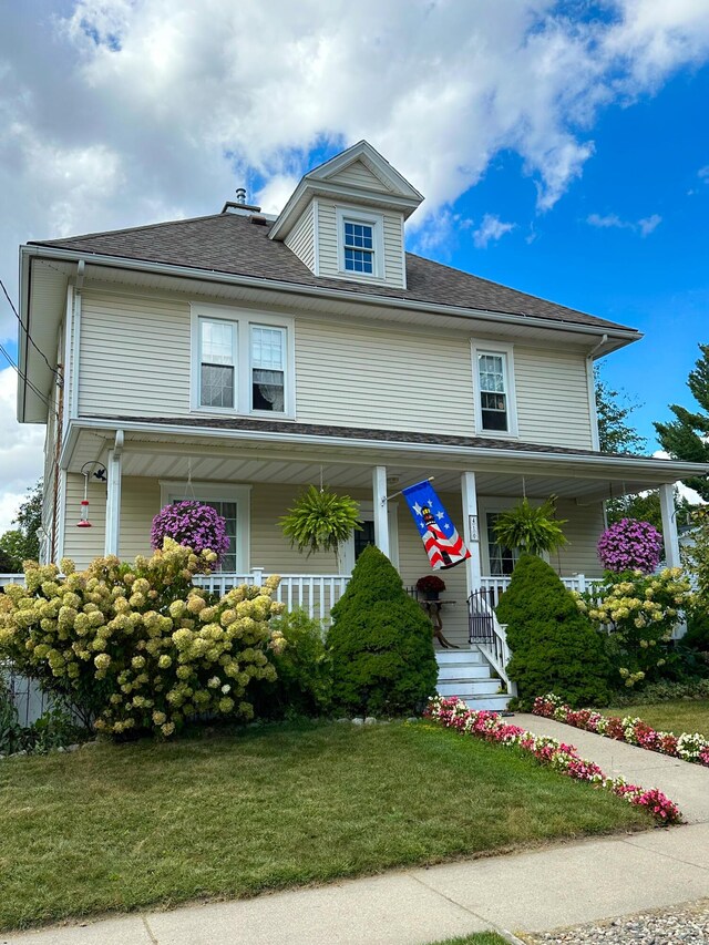 view of front of property featuring a porch, roof with shingles, and a front yard