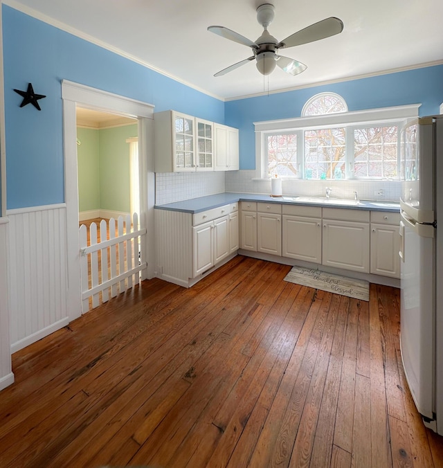 kitchen with freestanding refrigerator, a ceiling fan, dark wood-type flooring, backsplash, and glass insert cabinets
