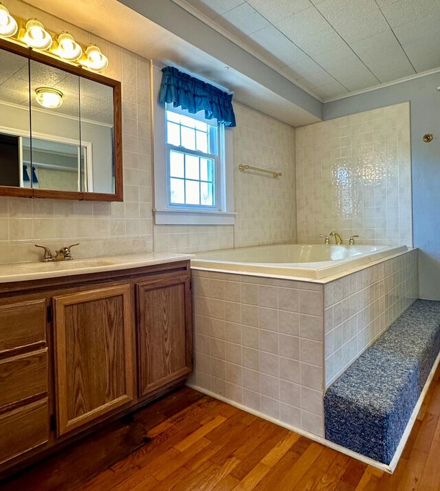 full bathroom featuring vanity, a garden tub, and wood finished floors