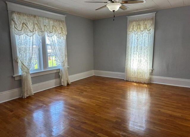 spare room with baseboards, a ceiling fan, and wood finished floors