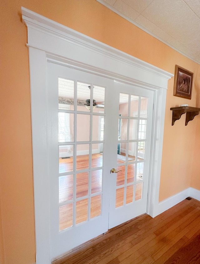 doorway with baseboards, ceiling fan, and wood finished floors