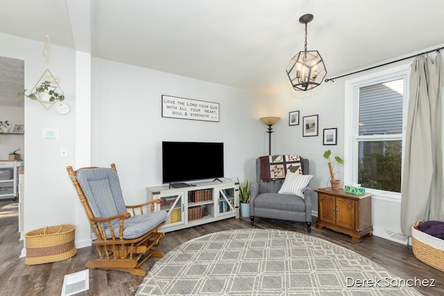 living area with baseboards, wood finished floors, and a notable chandelier