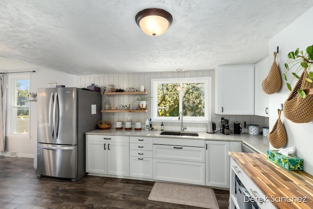 kitchen with freestanding refrigerator, a textured ceiling, a sink, and dark wood-type flooring