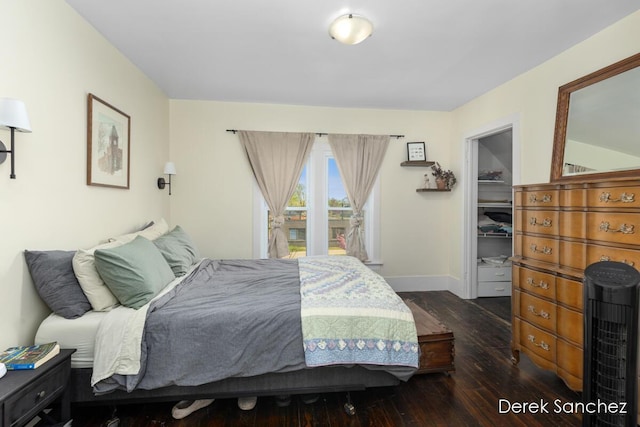 bedroom featuring baseboards, a walk in closet, a closet, and hardwood / wood-style flooring