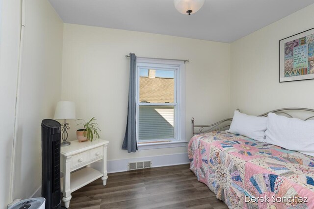 bedroom with baseboards, visible vents, and wood finished floors