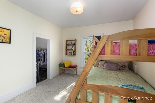 bedroom with a closet, baseboards, carpet flooring, and a walk in closet