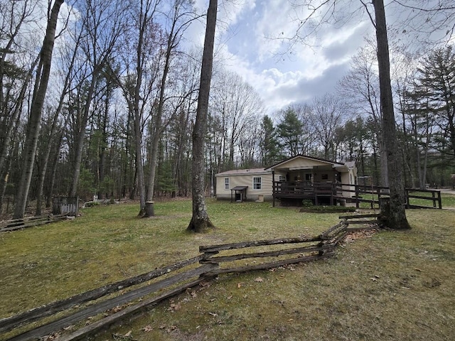 view of front facade featuring fence, a wooden deck, and a front yard