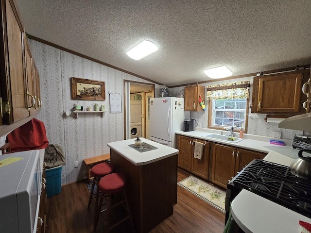 kitchen featuring a sink, a center island, freestanding refrigerator, lofted ceiling, and dark wood-type flooring