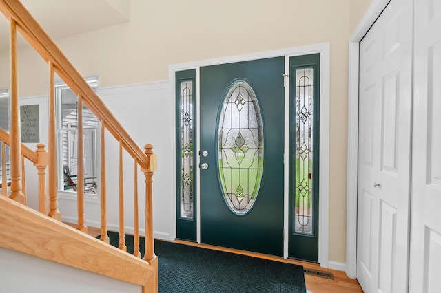 entrance foyer with stairs, baseboards, visible vents, and wood finished floors