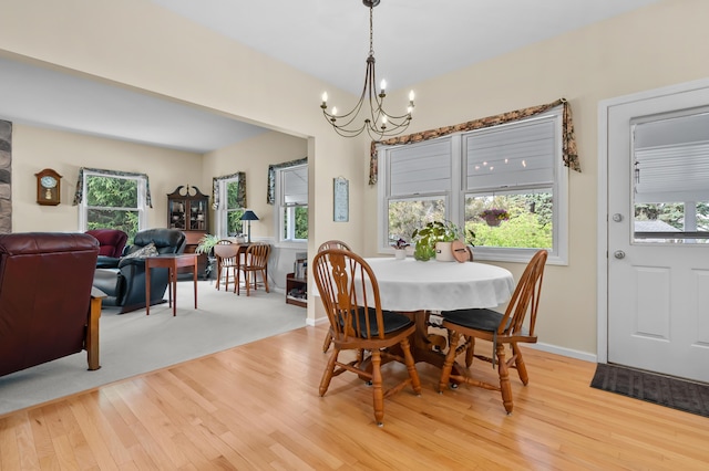 dining area featuring light wood-style floors, baseboards, and an inviting chandelier